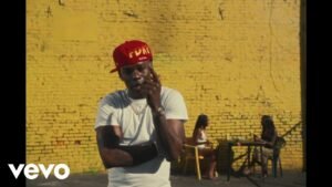 Rema singing in the music video for Oh No, wearing a dark jacket, standing in front of neon lights